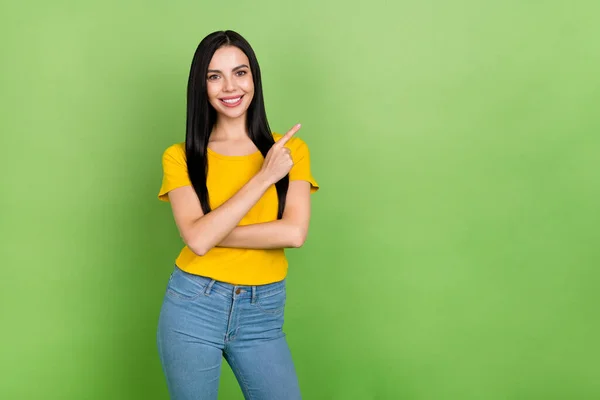 Photo of adorable cute woman wear yellow t-shirt smiling pointing empty space isolated green color background — Stockfoto