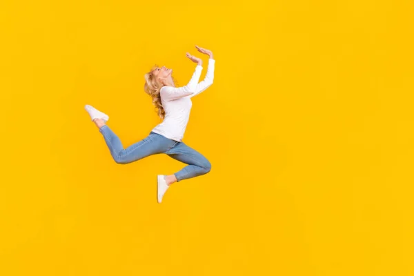 Full length photo of cute young blond lady jump wear shirt jeans sneakers isolated on yellow background — Stock Fotó