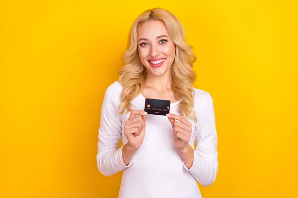 Foto de dulce adorable dama vestida camisa blanca levantamiento tarjeta de crédito aislado color amarillo fondo — Foto de Stock