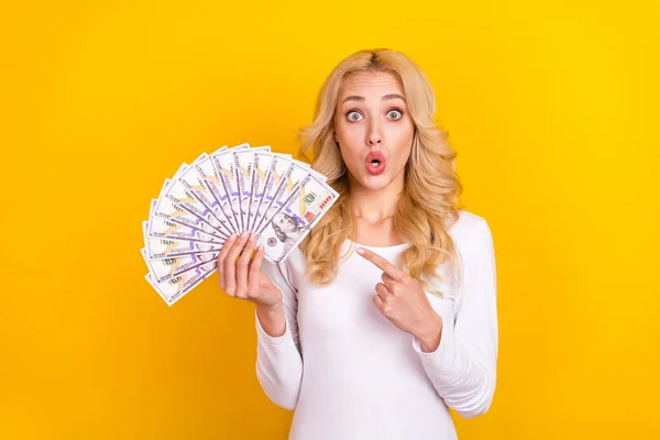 Photo of impressed cute lady dressed white shirt pointing cash fan big eyes isolated yellow color background — стоковое фото