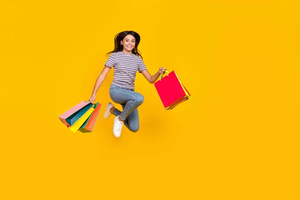 Foto de larga duración de la tienda de chicas excitadas jóvenes salto de descuento aislado sobre fondo de color amarillo —  Fotos de Stock
