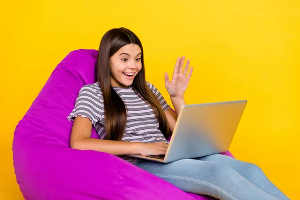 Profile side photo of young lady talk communication laptop wave hi sit chair isolated over yellow color background —  Fotos de Stock