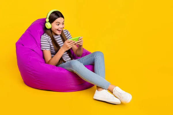 Full size profile side photo of young lady play videogame mobile phone sit chair weekend isolated over yellow color background — Zdjęcie stockowe