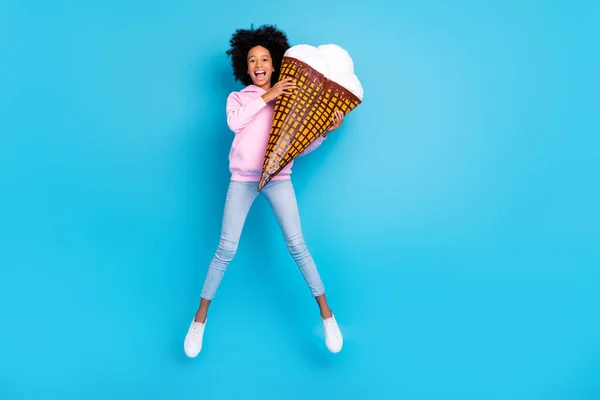 Foto de tamaño completo de chica joven divertirse salto enérgico celebración de helado grande aislado sobre fondo de color azul —  Fotos de Stock