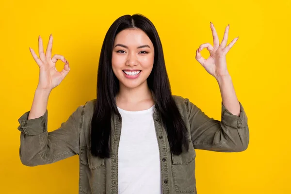 Photo of cheerful adorable girl showing okay symbol wear khaki jacket isolated on yellow color background — Stock Photo, Image
