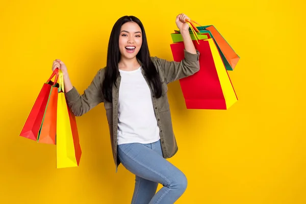 Photo of funky millennial brunette lady hold bags yell wear casual cloth isolated on yellow color background — Stockfoto