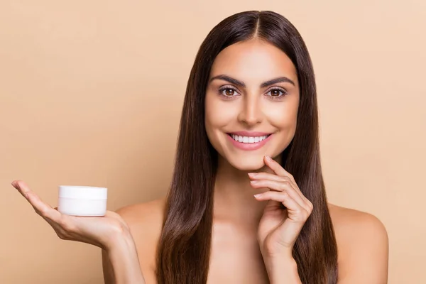 Portrait von attraktiven fröhlich gesundes Mädchen hält auf Handfläche tägliche Creme Lösung weiche Haut isoliert über beige Pastellfarbe Hintergrund — Stockfoto