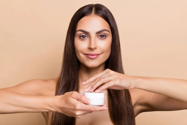 Portrait of attractive confident healthy girl holding using daily collagen cream perfection isolated over beige pastel color background — стоковое фото