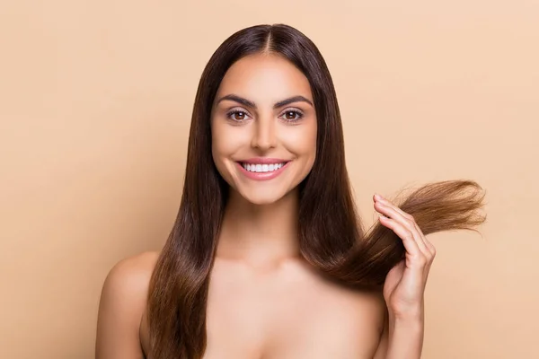 Retrato de chica atractiva alegre y saludable de pelo largo sosteniendo extremos secos solución máscara de bálsamo aislado sobre fondo de color pastel beige — Foto de Stock