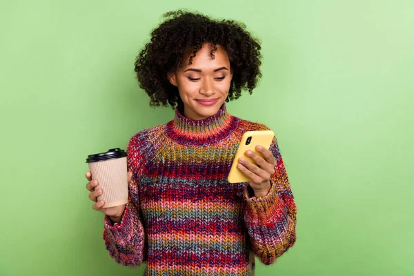 Foto van aantrekkelijke dame houden koffie gebruik telefoon chatten genieten pauze geïsoleerd op groene kleur achtergrond — Stockfoto