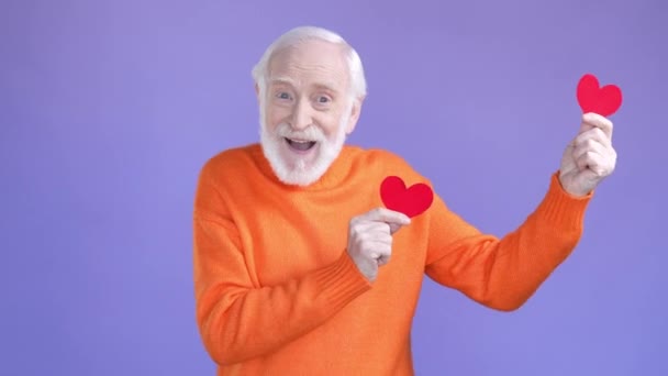 Positive aged man dancing small card hearts isolated vivid color background — Stok video