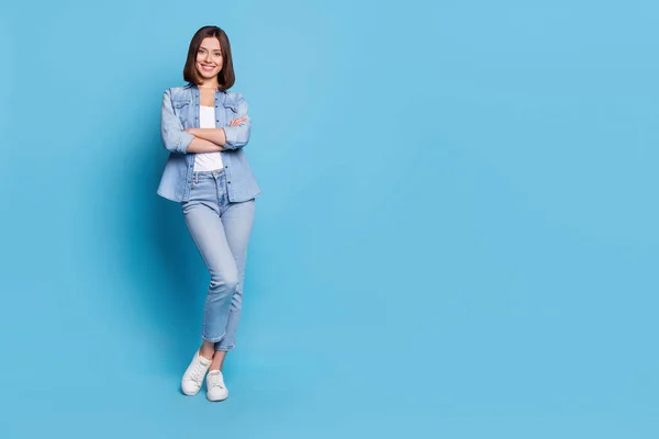 Kuva luottavainen viehättävä nainen käyttää farkut paita kädet ristissä hymyillen eristetty sininen väri tausta — kuvapankkivalokuva