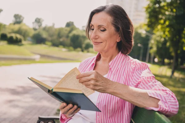 夢のような美しい女性の年金受給者の写真ピンクのシャツを着て面白い話を読む屋外の田舎の庭 — ストック写真