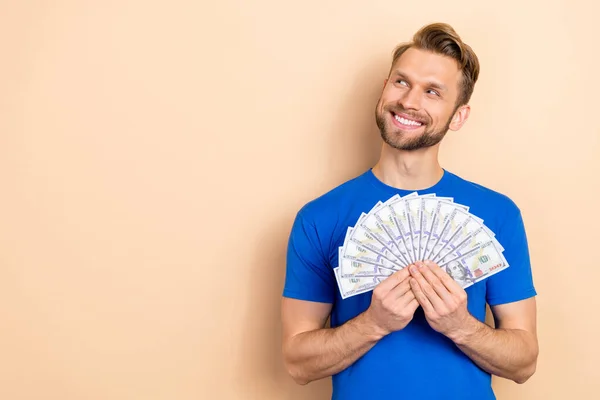 Photo of young man wonder dreamy look empty space hold cash profit salary isolated over beige color background — Stock Photo, Image