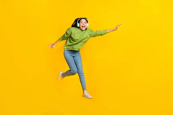 Full size photo of young cheerful girl have fun jump fly meloman sound isolated over yellow color background — Stock fotografie