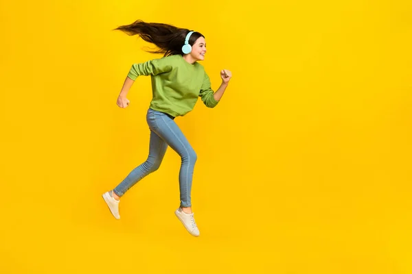 Full size profile side photo of young girl runner jumper rush speed meloman isolated over yellow color background — Zdjęcie stockowe