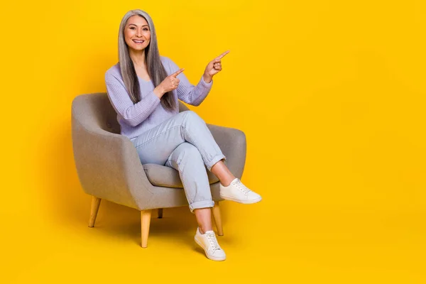 Full length photo of cheerful good mood grandma promoting furniture shop isolated on yellow color background — 스톡 사진