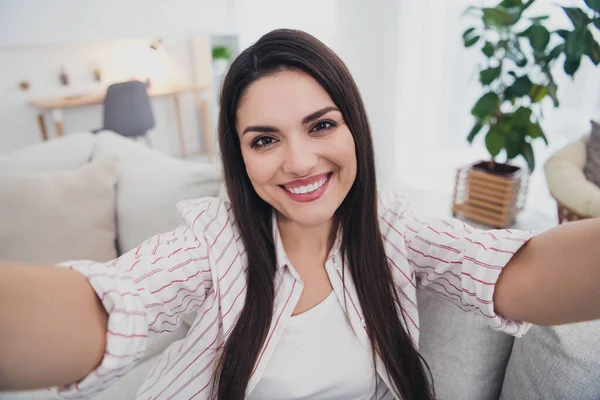 Zelfportret van een aantrekkelijke vrolijke langharige vrouw die op divan zit en overdag thuis verblijft — Stockfoto