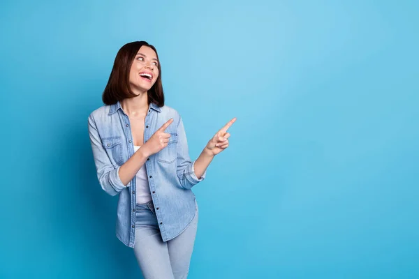 Photo of sweet dreamy lady dressed denim shirt pointing two fingers empty space isolated blue color background — ストック写真