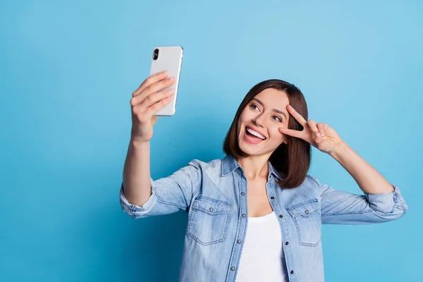 Photo of cheerful pretty girl make selfie hand make show v-sign isolated on blue color background — Fotografia de Stock