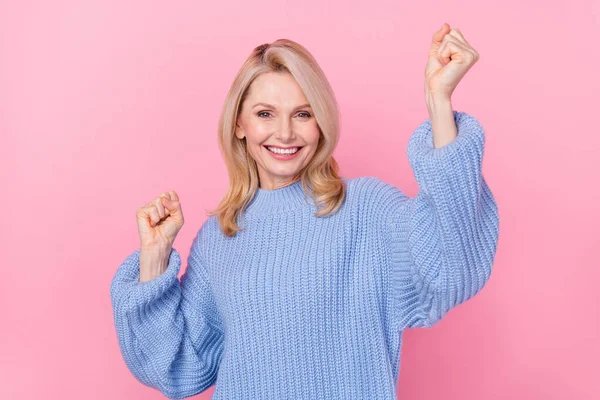 Foto av Hurra mogen blond dam händer nävar bära blå tröja isolerad på rosa färg bakgrund — Stockfoto
