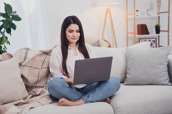 Ritratto di attraente donna dai capelli lunghi specializzata copywriter seduta sul divano utilizzando il computer portatile a distanza a casa all'interno — Foto Stock