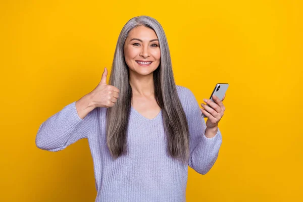 Tarz sahibi gri saçlı modern büyükannenin fotoğrafı sarı arka planda izole edilmiş sosyal medya akıllı telefonunu tavsiye eder. — Stok fotoğraf