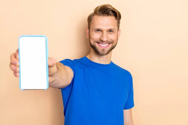 Photo of young cheerful man demonstrate mobile phone promo recommend isolated over beige color background — Stok fotoğraf