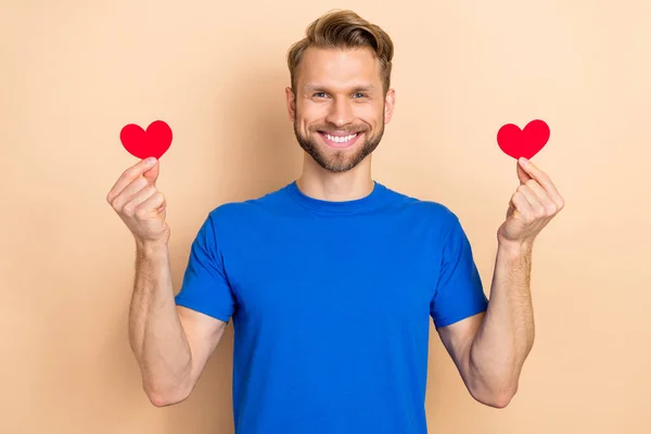 Photo of young cheerful guy hold little paper heart shape romantic cardiac isolated over beige color background — Fotografia de Stock