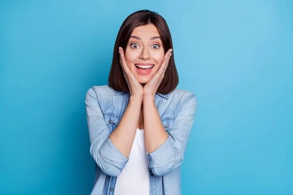 Photo of impressed shiny woman wear jeans shirt arms cheeks open mouth isolated blue color background — Stockfoto