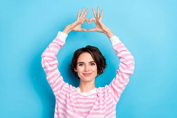 Foto de jovem linda menina positiva mostrando símbolo do coração acima da cabeça adorar admirar isolado no fundo de cor azul — Fotografia de Stock