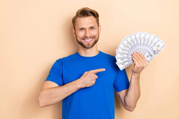 Photo of young guy indicate finger money suggest recommend profit isolated over beige color background — Stockfoto
