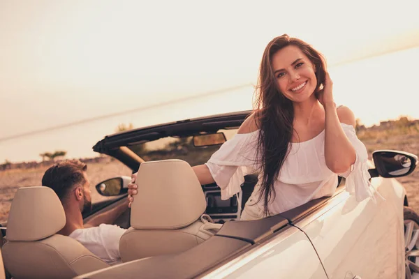 Cabriolet arabasıyla kumlu sahilde beyaz elbiseli, sıcak yaz havasının tadını çıkaran fotoğrafçı kadın. — Stok fotoğraf