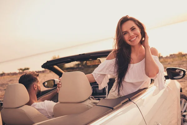 Photo portrait woman riding in cabriolet car on sandy beach wearing white dress enjoying warm summer weather — Stok fotoğraf