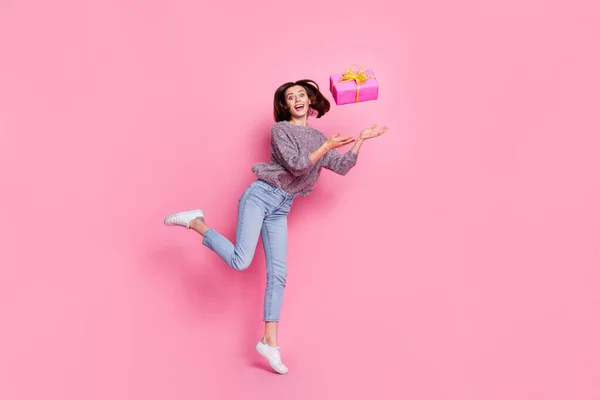 Foto de bonito impressionado senhora vestido suéter jogando presente saltando alto isolado cor de fundo rosa — Fotografia de Stock
