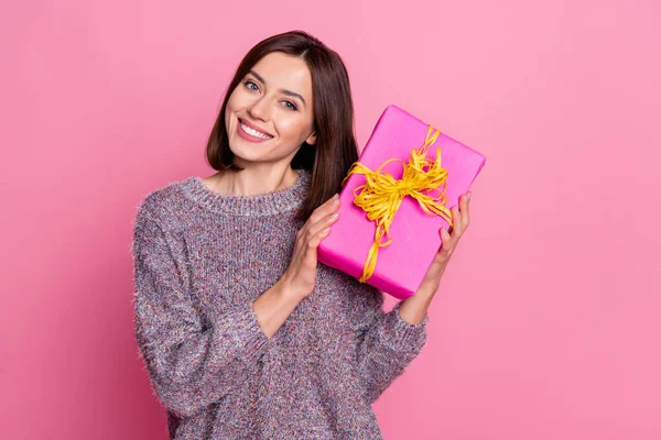 Portrait of attractive cheerful girl holding in hands festal gift 8 March isolated over pink pastel color background — стоковое фото