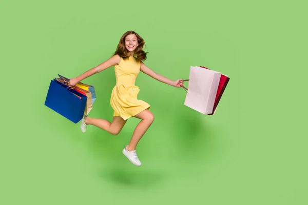 Full size profile side photo of excited cheerful teen blonde haired girl running shopping isolated on green color background — Stock fotografie
