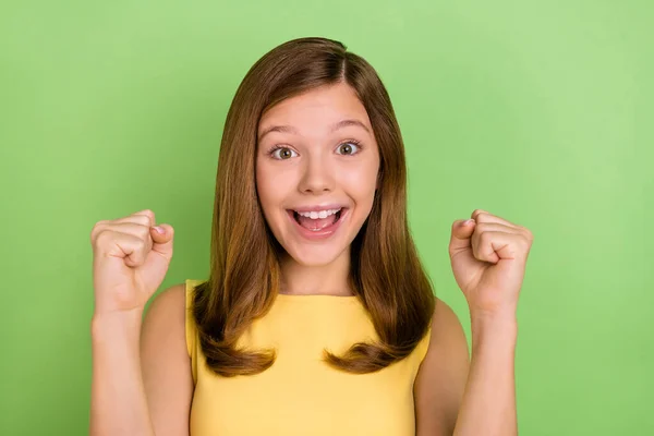 Portrait of cheerful blonde haired little lady raise fists in success triumph fan champion isolated on green color background — Stockfoto