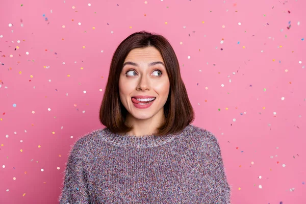 Portrait of attractive brown-haired funky cheerful girl flying confetti licking lip isolated over pink pastel color background — стоковое фото