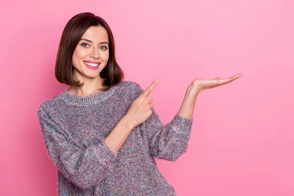 Portrait of attractive cheerful girl holding on palm demonstrating copy space ad gift isolated over pink pastel color background — Stockfoto