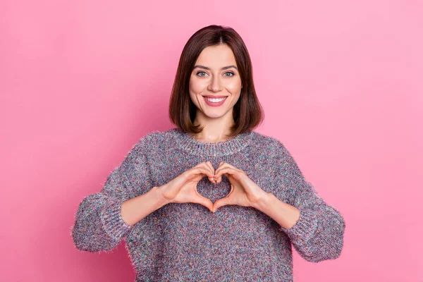 Portrait of attractive cheerful girl showing heart symbol care isolated over pink pastel color background — ストック写真