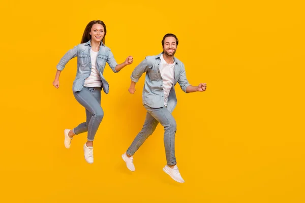 Full length body size view of beautiful handsome people jumping going shop isolated over bright yellow color background — Stok fotoğraf