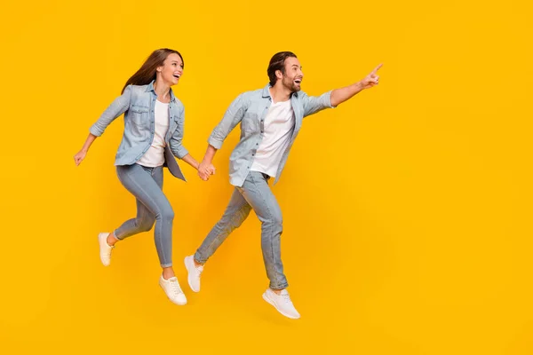 Full length body size view of beautiful handsome couple jumping showing copy space isolated over bright yellow color background — Stock Fotó