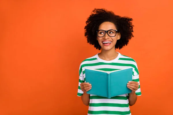 Portrait of attractive cheerful wavy-haired girl reading book copy space solution advert isolated over bright orange color background — ストック写真