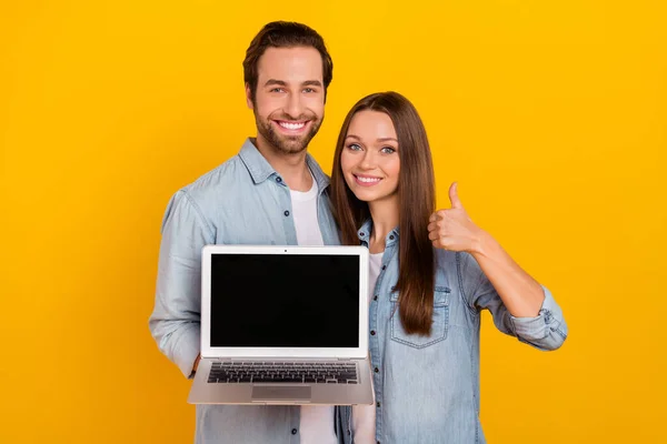 Portré jóképű szép vidám pár gazdaság laptop mutatja hüvelykujj elszigetelt felett élénk sárga színű háttér — Stock Fotó