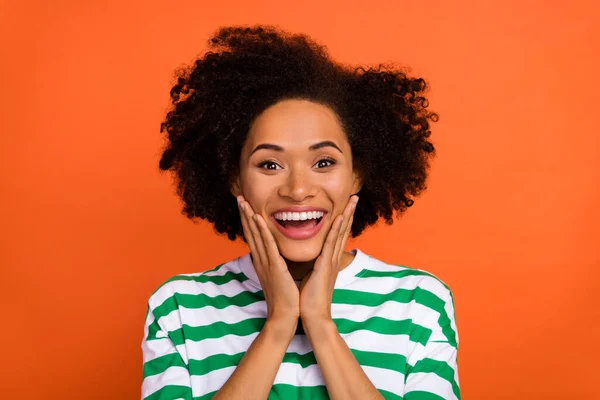 Portrait of attractive amazed cheerful wavy-haired girl good news reaction isolated over vibrant orange color background — стоковое фото