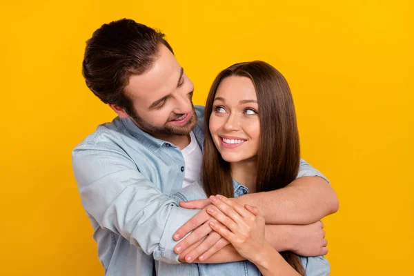 Photo of impressed millennial brown hairdo couple hug look wear blue shirt isolated on yellow background — Zdjęcie stockowe