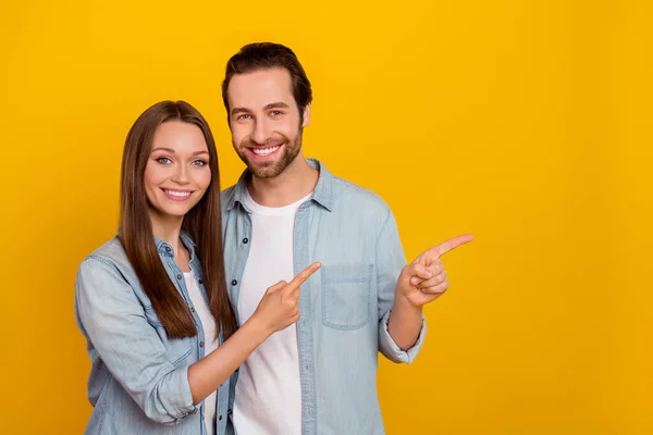 Photo of nice young brown hairdo couple index promo wear jeans shirts isolated on yellow background — Zdjęcie stockowe