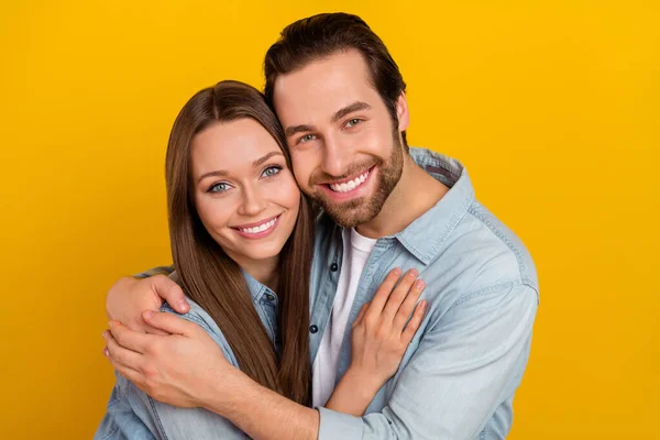 Foto de alegre namorado positivo namorada vestida camisas jeans abraçando sorrindo isolado cor amarela fundo — Fotografia de Stock