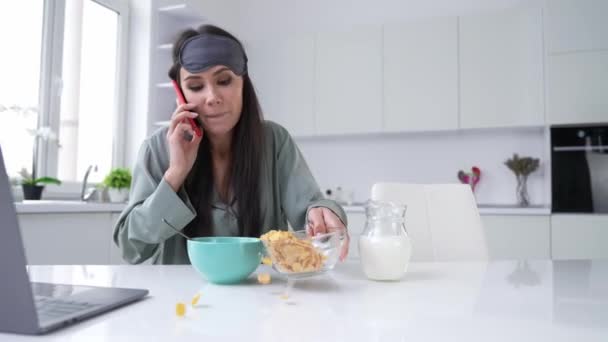 Lady oversleep panic call boss smartphone eat musli in light kitchen — Stok video